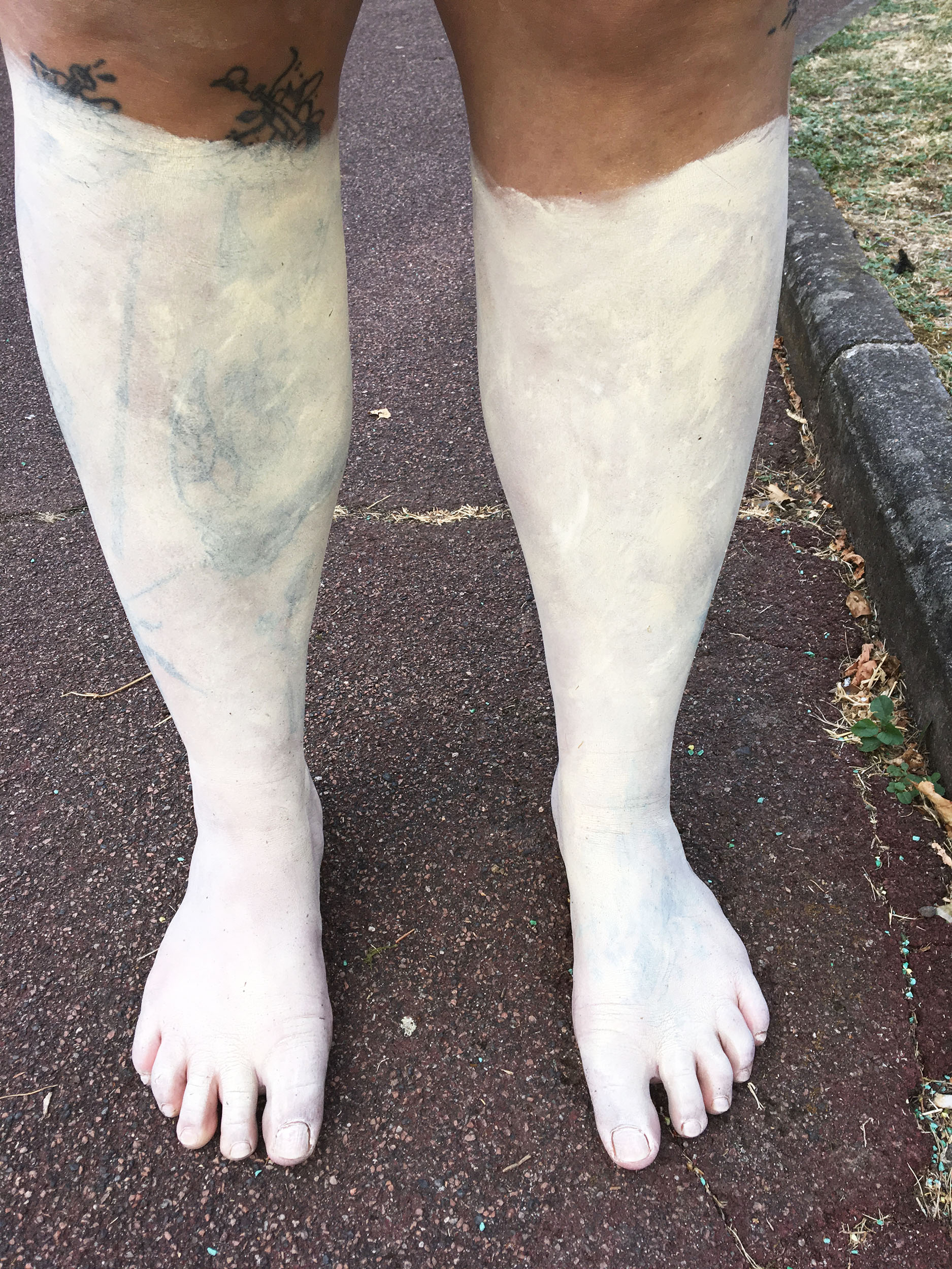 Des jambes sont recouvertes de maquillage blanc aux reflets dorés